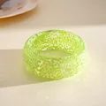 Macro detail view of a vibrant translucent green resin bangle with iridescent glitter inclusions. - Green