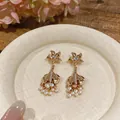Detailed shot of vintage gold palace-style earrings with pearls and crystal accents - Fish Tail Pearl Drop Style (HE33491 HE33754) / Gold-White