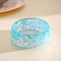 Close-up of translucent light blue resin bangle with iridescent geometric inclusions - Blue