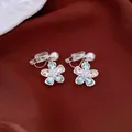 Detail view of flower-shaped clip-on earrings with green rhinestones and pearls - Clip-On Earrings / Silver-Blue
