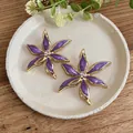 Eleganti orecchini a lobo a fiore in smalto viola con cristalli centrali e placcatura oro. - Viola