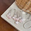 Makroansicht feiner Quastenohrringe aus rosa Harzblumen auf einem Vintage-Buchcover - Silber-Ohrstecker - Rosa
