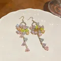 Close-up of colorful lily of the valley flower tassel earrings on white plate - Ear Hook Tassel Style / Gold Multicolor
