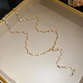Detailed view of a gold-tone necklace with white beads in a beige jewelry tray - Gold, White