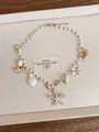 Dettaglio di collana di perle con ciondoli a stella marina e conchiglie per vacanza - Collana / Oro-Bianco