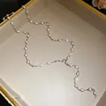 Detail view of an elegant acrylic pearl necklace with silver links on a beige jewelry tray - Silver, White