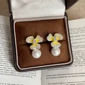 Primer plano de pendientes de flor amarilla con elegantes perlas colgantes en estuche. - Pin de Plata-Plata-Amarillo