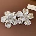 Detailed macro view of shiny silver metallic flower statement earrings on leather base. - Silver