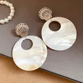 Nahaufnahme von runden Perlmuttohrringen mit silbernen Muschelsteckern - Silber
