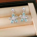 Primo piano di orecchini a fiore argentati con cristalli blu e perle in scatola. - Stile Fiore / Blu