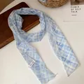 Primer plano de un collar tipo bufanda de malla a cuadros azules y blancos sobre una mesa - Cuadros Azul Blanco