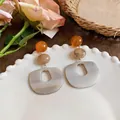 Dettaglio degli orecchini retrò in acetato con gocce geometriche rosa e marmorizzate. - Stile geometrico retrò / Bianco-Caffè