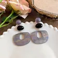 Primo piano di orecchini vintage in acetato di marmo viola con pendenti ovali geometrici - Stile geometrico retrò / Grigio