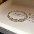Detail shot of a silver-toned 18K gold-plated bangle with square pavé-set zircon links - Square Hollow Style