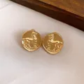Close-up macro detail of vintage matte gold round stud earrings with horse motif - Gold