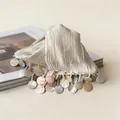 Detailed macro view of a cream fabric hair claw clip with iridescent shell disc tassels. - Hair Claw / White