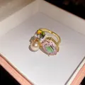 Macro view of a vintage style gold-tone open ring featuring oval crystal and pearl detail - Gold-Pink