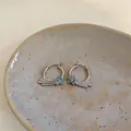 Nahaufnahme französischer Creolen mit blauem Zirkonstern-Design auf einer Keramikschale - Ohrbuckle / Silber