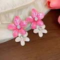 Vista dettagliata di orecchini a fiore in smalto rosa e bianco con strass scintillanti - Perno in acciaio inossidabile - Oro / Rosa