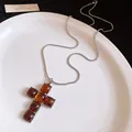 Detailed close-up of a vintage resin cross pendant on a sleek silver snake chain necklace - Silver