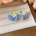 Vue macro détaillée de boucles d'oreilles fleurs en perles de verre colorées faites main - Boucles d'oreilles à clip / Bleu-Violet
