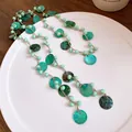 Vista ravvicinata della collana bohémien con perline verdi e conchiglie su piatto bianco - Collana (HN12064) / Verde