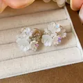 Gros plan d'élégantes boucles d'oreilles fleurs en perles de verre faites à la main - Boucles d'oreilles à clip / Blanc