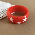 Vue macro d'un bracelet en résine rouge avec motif d'étoiles blanches et finition brillante - Orange