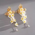 Dettaglio di orecchini pendenti con fiori di vetro bianchi e foglie dorate. - Perno in Argento Nappa di Fiori / Oro-Bianco-Giallo