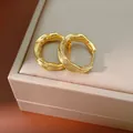 Close-up of elegant 18k gold plated crumpled textured hoop earrings on a jewelry box - Gold
