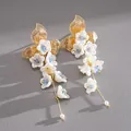 Dettaglio ravvicinato di eleganti orecchini a nappa dorati con fiori in vetro e perle - Perno in Argento Nappa di Fiori / Oro-Bianco-Blu