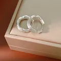 Detailed macro view of 18k gold plated silver crumpled texture hoop earrings on box - Silver