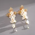 Dettaglio di orecchini a nappa con fiori bianchi, foglie dorate e perle eleganti. - Perno in Argento Nappa di Fiori / Oro-Bianco