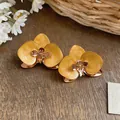 Detailansicht der gelben Orchideen-Ohrstecker mit Emaille-Finish im Vintage-Stil - Gelb