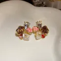 Close-up of elegant floral stud earrings with sparkling crystals and pink beads - Red-Pink