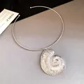 Close-up of a silver nautilus shell pendant necklace on a gray textured surface - Seashell Pendant Choker / Silver