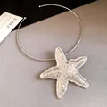 Detailed view of a large metallic silver starfish pendant on a minimalist wire choker necklace. - Starfish Pendant Choker / Silver