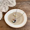 Dettaglio di una collana con pendente a forma di gatto nero e ombrello pastello e perle. - Blu Rosa