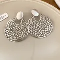 Nahaufnahme der eleganten, silberfarbenen, runden Hohlohrringe auf einem cremefarbenen Teller - Runder Hohler Stil (Silber) / Silber