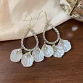 Detailed view of elegant drop earrings with white shell petals and shimmering rhinestones - Ear Hook Style
