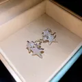 Detail of silver star-shaped ear cuffs encrusted with shimmering cubic zirconia stones - Clip-On Earrings / Silver