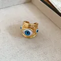 Close-up of a gold-toned adjustable open ring featuring a vivid blue evil eye design. - Evil Eye Style / Gold