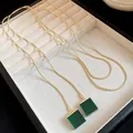 Close-up detail of vintage gold snake chain necklace with square green resin pendant - Necklace / Gold-Green