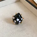 Detailed view of a cute black enamel ladybug ring featuring white heart patterns - Black Ladybug Style / Gold