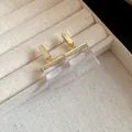 Close-up detail shot of clear square resin pendant earrings in a beige velvet jewelry box - Earrings / Gold-White