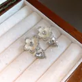 Close-up view of elegant silver flower and crystal heart drop earrings in a wooden jewelry box - Gold