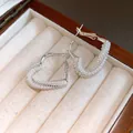 Detailed view of silver-toned heart earrings with pearl inlay in a jewelry box - Silver White