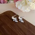 Macro view of silver stud earrings featuring delicate clear crystal drop charms - Silver Bow Style (Alloy)