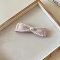 Elegante Nahaufnahme einer rosa Satin-Schleifen-Haarspange mit feinem Perlenbesatz - Perlenstil / Einzelstück / Rosa