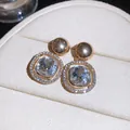 Close-up of geometric halo crystal earrings with a sparkling starburst effect - Gold